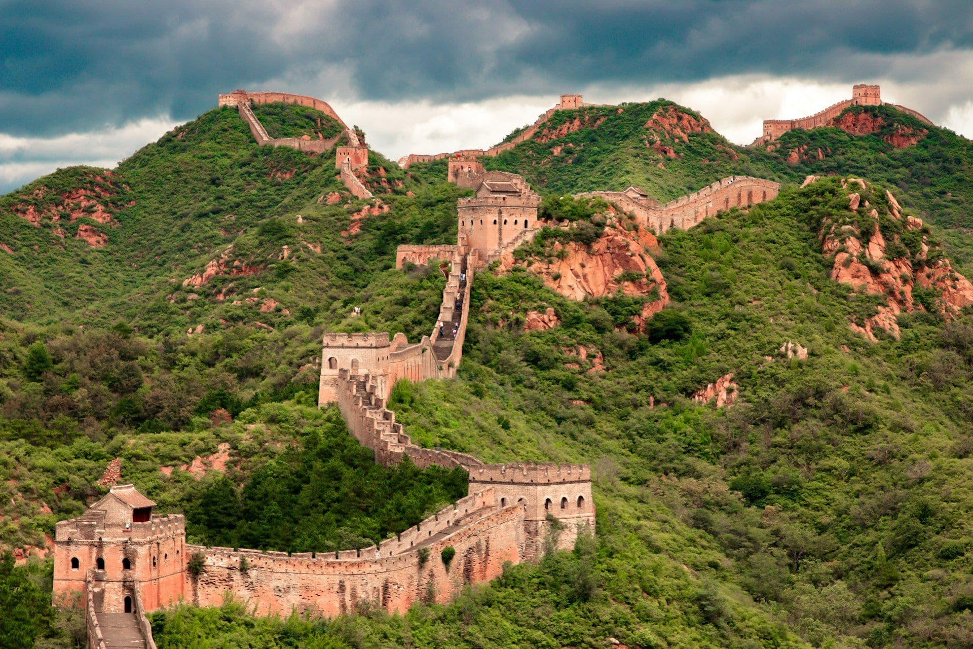 A Grande Muralha da China serpenteando por colinas verdes